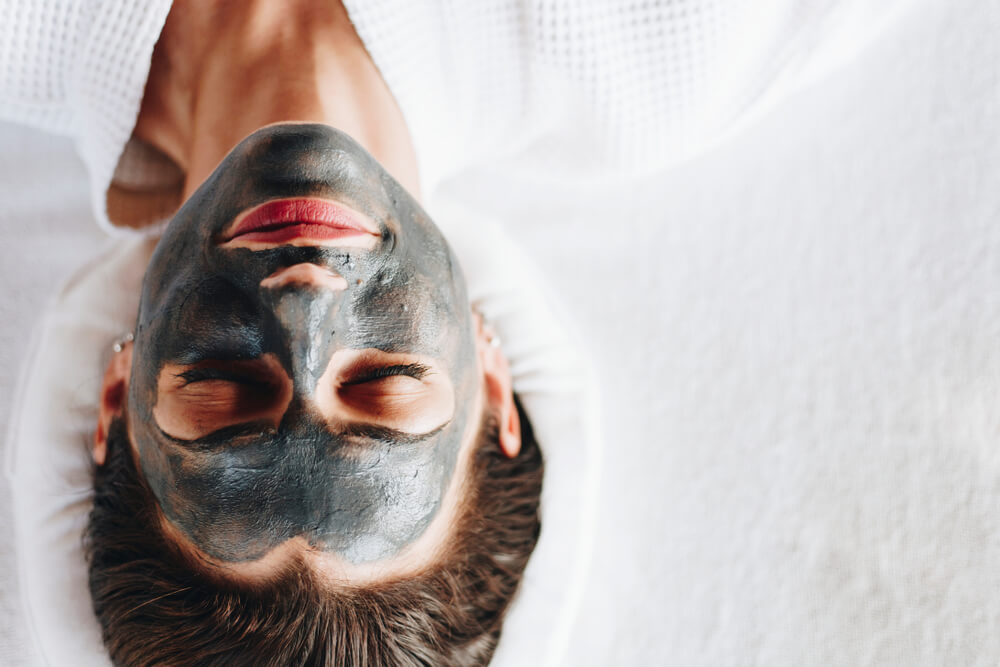 Woman relaxing with a charcoal face mask 