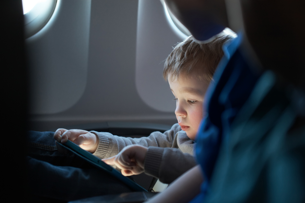 Child playing on a tablet in an airplane. 