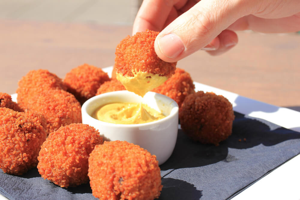 Unknown hand dipping bitterballen into dipping sauce